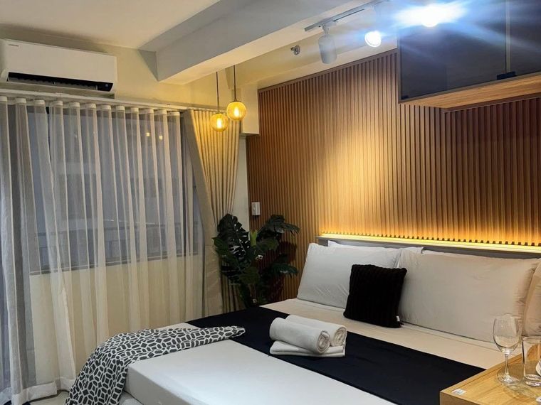 Bedroom with a slatted timber headboard wall, concealed strip lighting, track lighting and a raised bed platform