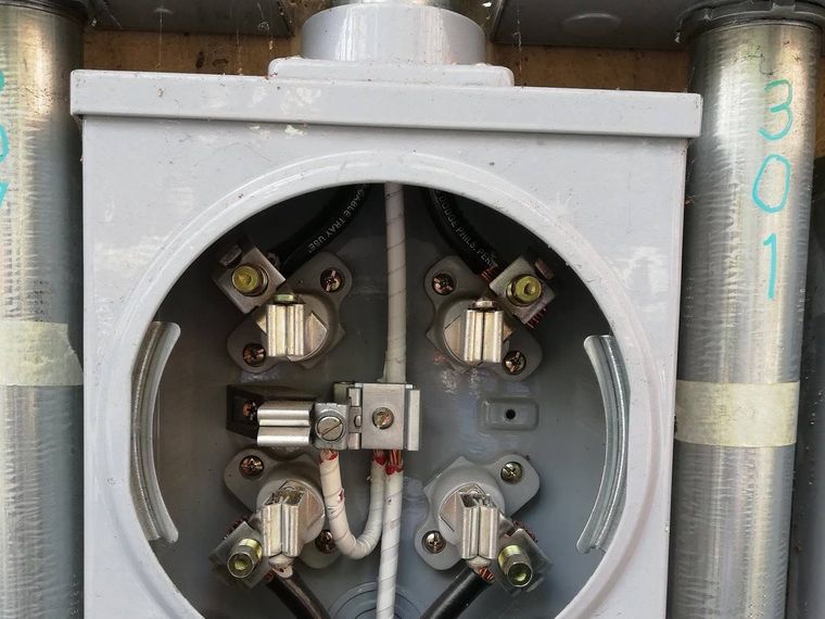 Utility meter socket wired and terminated, with service conduits marked by unit number
