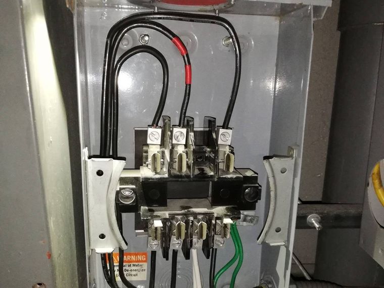 Interior of a metering enclosure showing line and load terminations and earth conductor