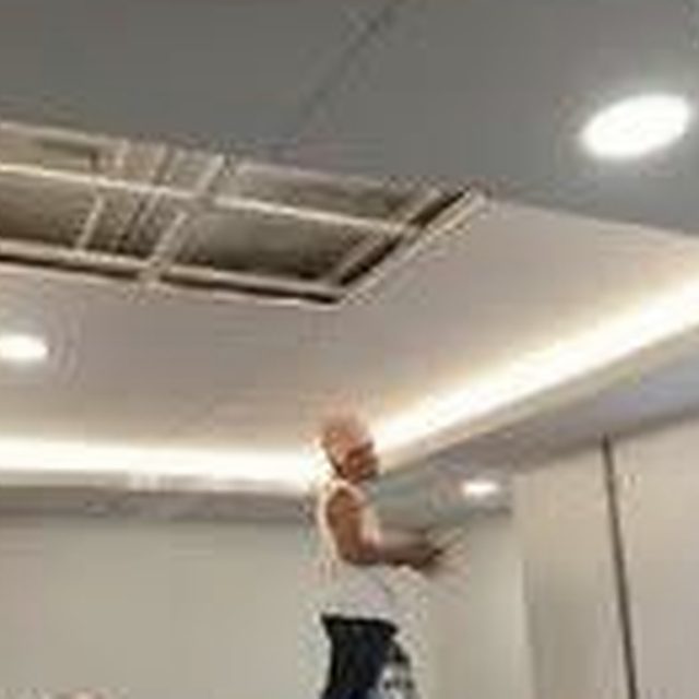 Ceiling cassette air-conditioning unit being fitted into a dropped ceiling