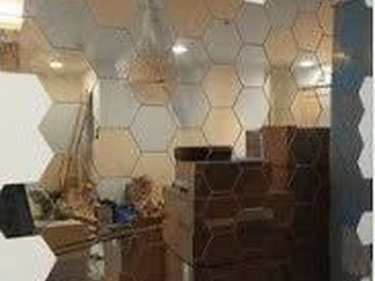 Mirrored hexagonal tiles being set out across a feature wall during installation